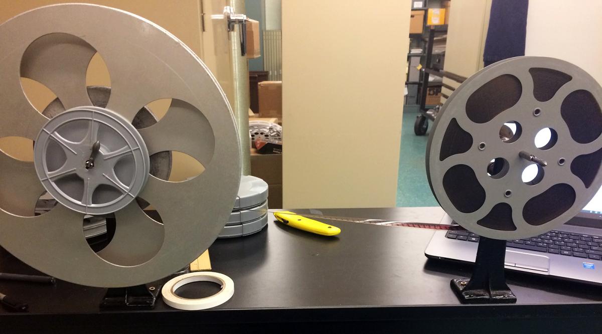 Film on a metal reel, tape and a knife lie on the table