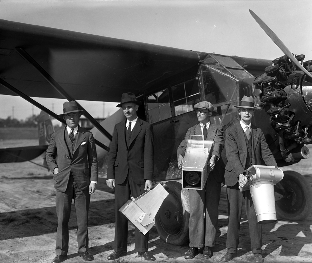 Victor Dallin and his staff with cameras in front of an airplane
