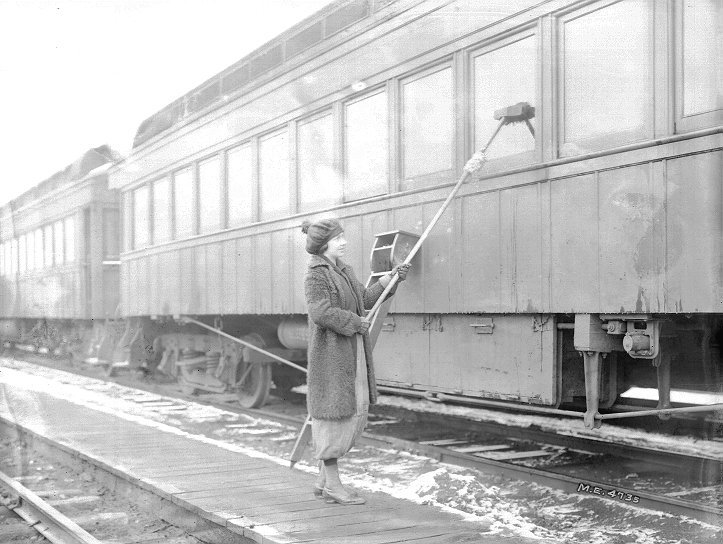 Female worker cleans train windows