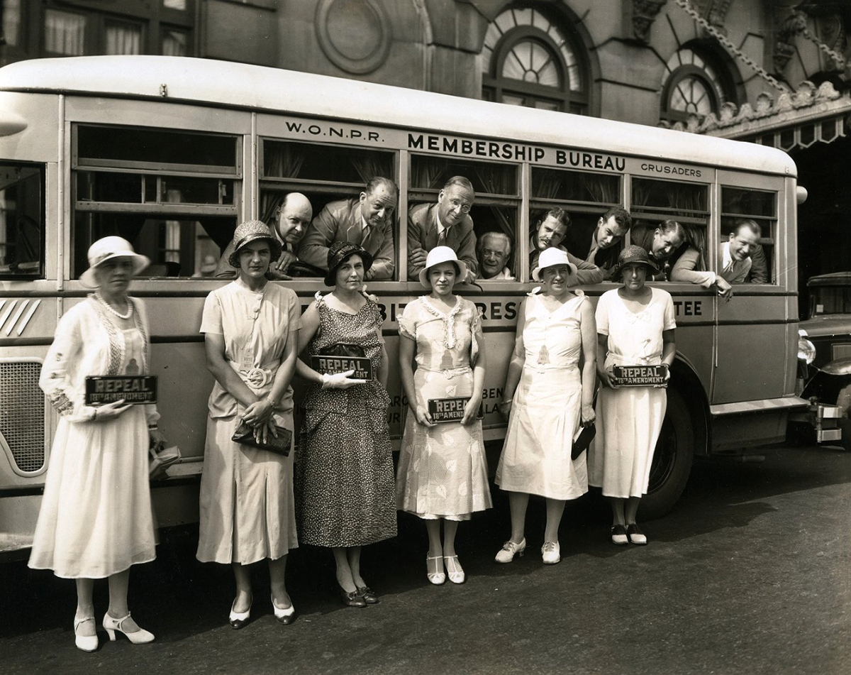 Women at a prohibition rally with bus and "repeal" signs.