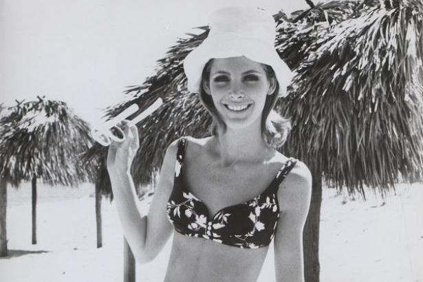 woman in bikini poses in front of palm trees