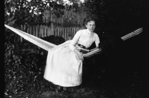 Black and white image of a woman in a hammock with a book.