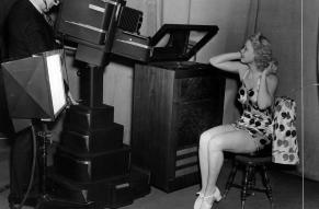 Toby Wing, screen and stage star, watches herself in the television receiving set as she performs before the new television equipment in the Philco Radio television station 